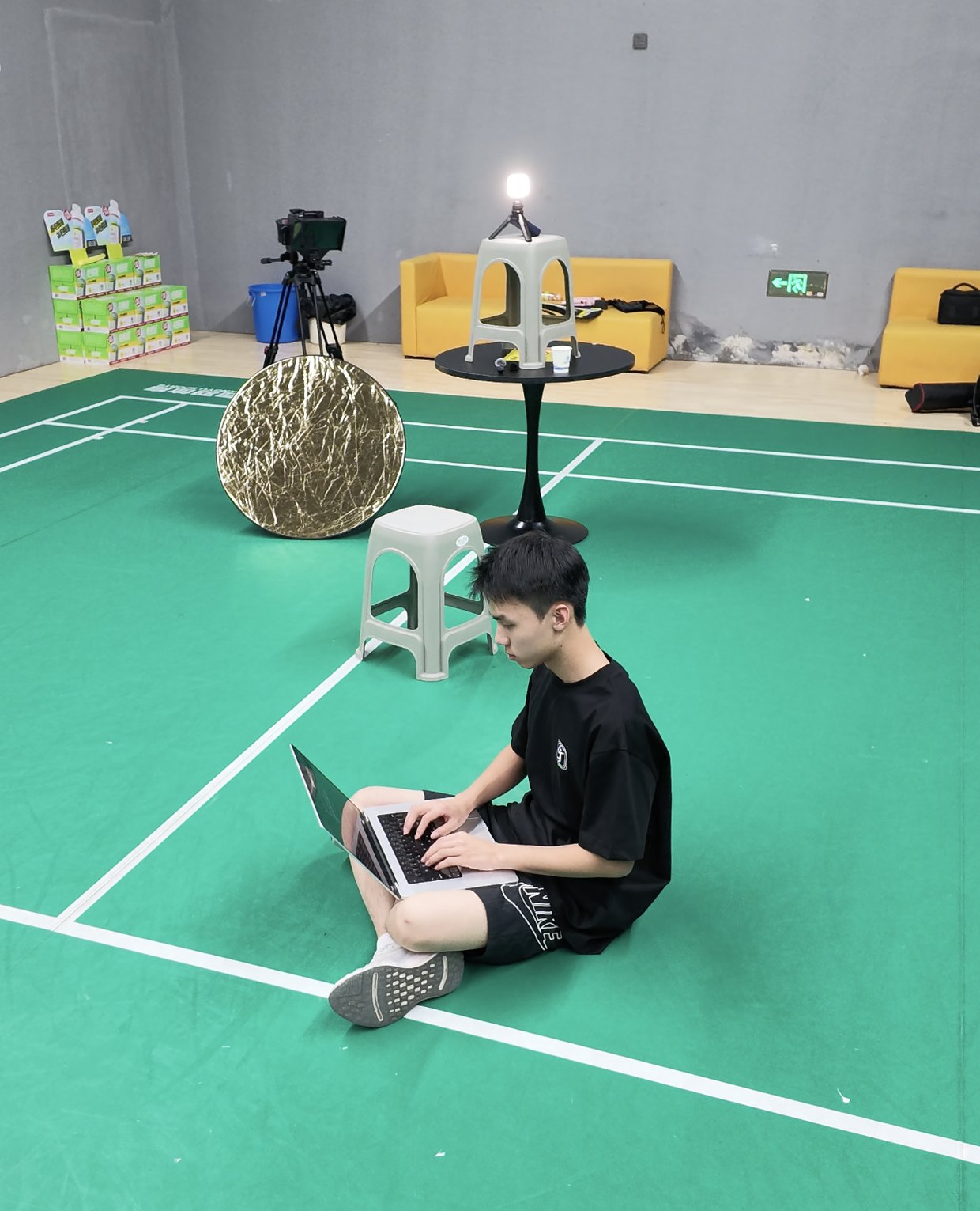The developer sitting on the court floor, processing footage on a laptop